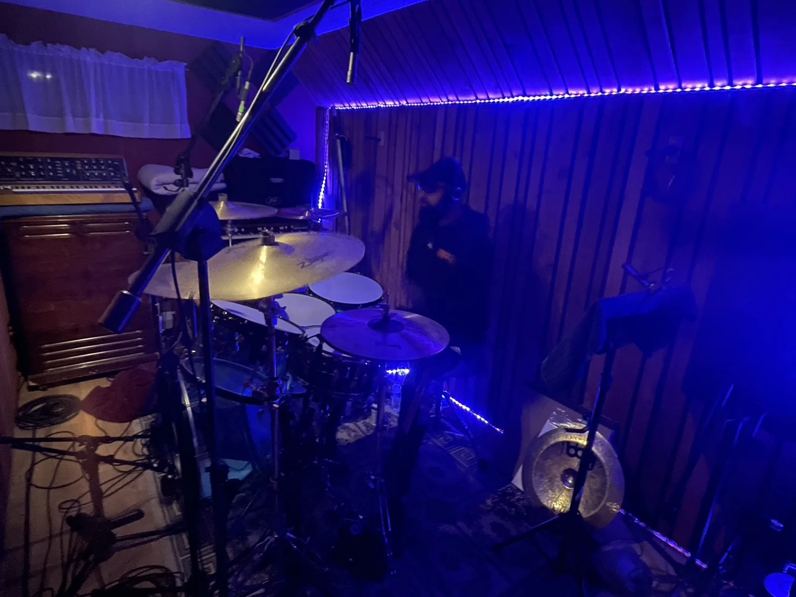 A drummer at the kit under blue studio lighting