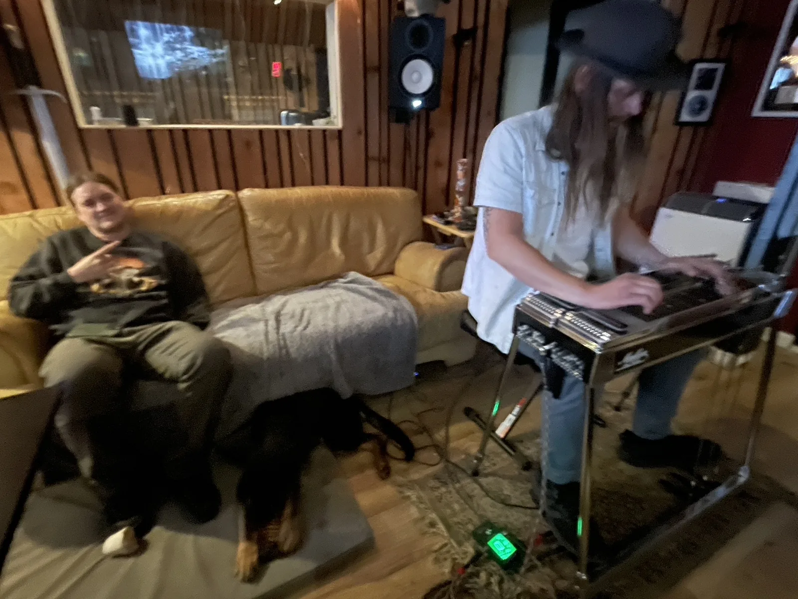 A musician playing a lap steel beside the studio couch