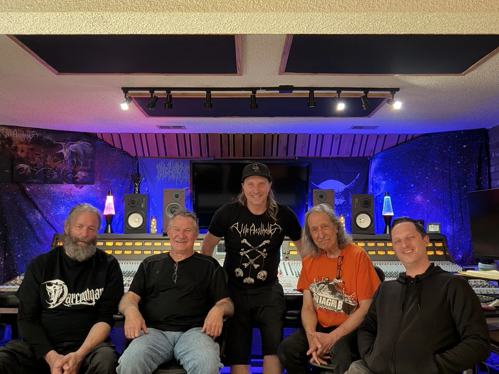 Five people together in front of the studio console